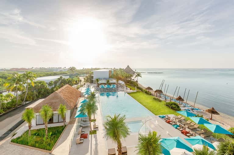 Aerial view of luxury beachfront resort with infinity pool, palm trees, and turquoise ocean