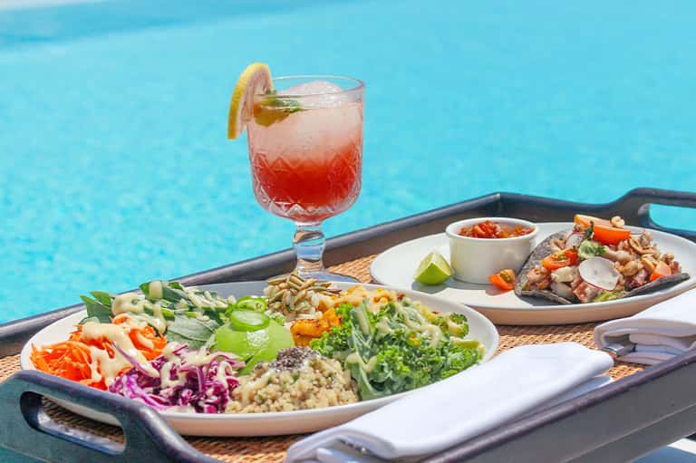 Poolside cocktail and appetizer plates with colorful salad and grilled items