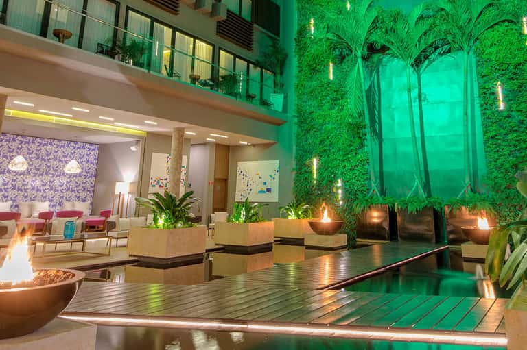 Modern hotel lobby with green living walls, fireplace, lounge seating, and contemporary lighting