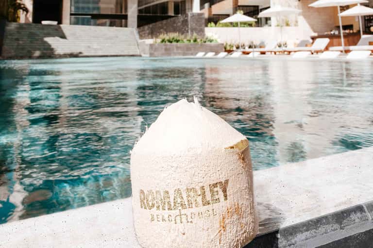 Coconut drink by pool at Romarley Beach Club resort with lounge chairs