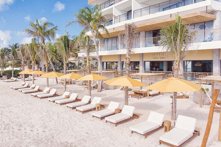 Beachfront resort with lounge chairs under yellow umbrellas and palm trees