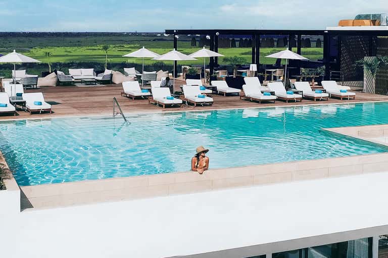 Resort pool with turquoise water, white loungers with umbrellas, and modern deck area
