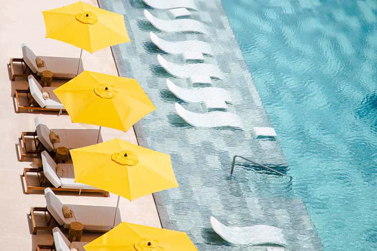 Overhead view of luxury resort pool with yellow umbrellas over lounge chairs and turquoise water