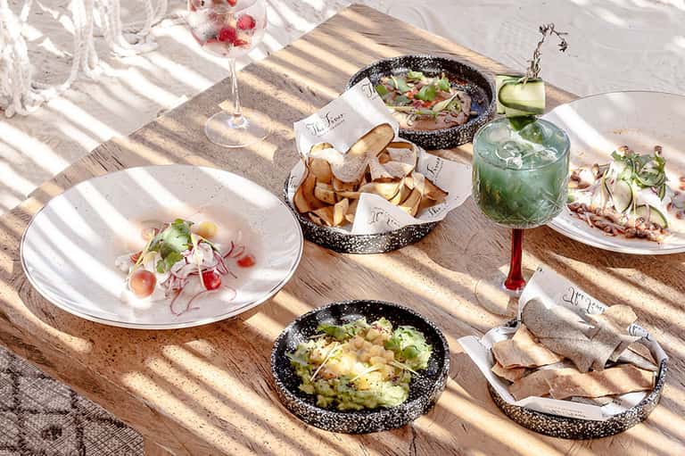 Beachside dining table with appetizers, cocktails, and coastal sunlight