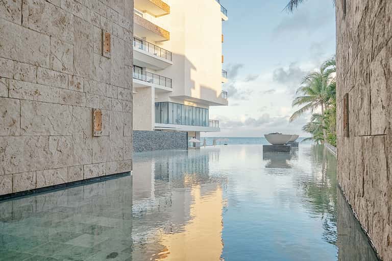 Luxury infinity pool blending seamlessly with ocean view between stone building walls