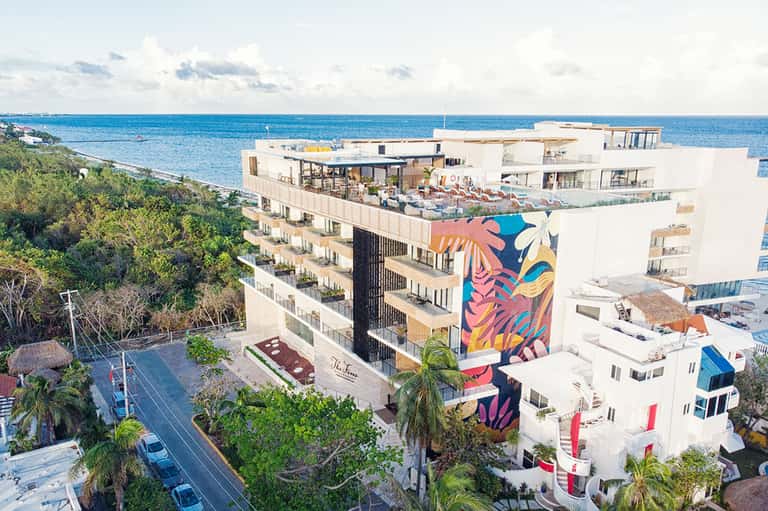 Beachfront hotel with colorful street art mural, ocean views, and multi-story white architecture