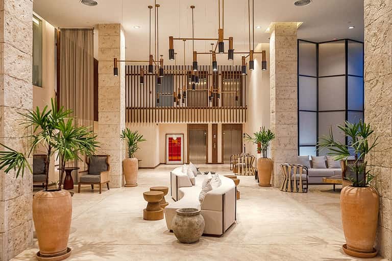 Luxury hotel lobby with soaring ceilings, pendant lighting, and travertine flooring