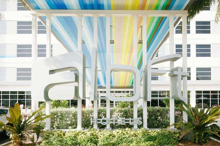 Colorful striped pergola canopy over modern resort courtyard with landscaping