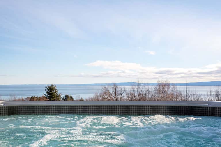 Infinity pool overlooking a tranquil lake with bare winter trees on the shoreline
