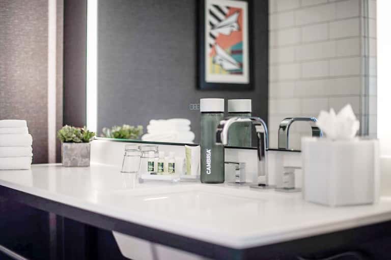 Modern bathroom vanity with white sink, faucet, and toiletries on white countertop