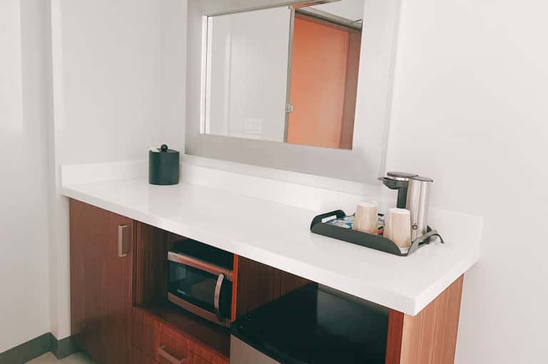 Modern bathroom vanity with white countertop, wooden cabinets, and large mirror