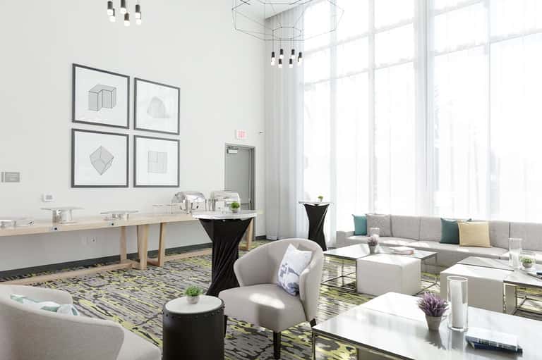 Contemporary hotel lounge with seating areas, geometric wall art, large windows, and modern decor