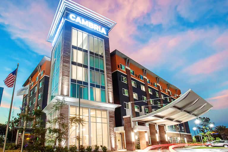 Modern Cambria hotel exterior at dusk with illuminated signage and brick architecture
