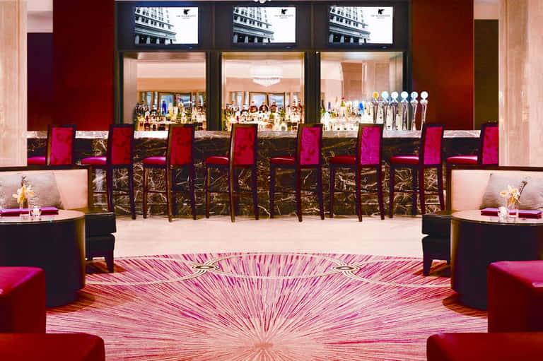 Luxury jewelry store interior with magenta velvet chairs, display cases, and three large screens above storefront windows