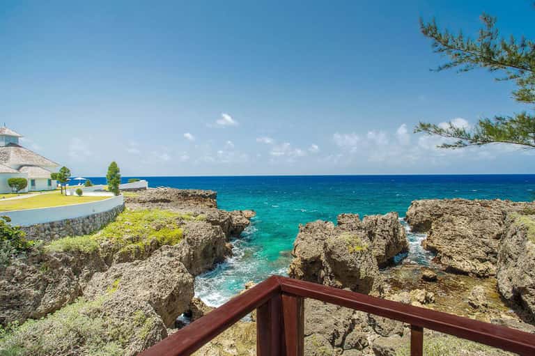 Turquoise ocean cove with rocky limestone formations and white waterfront building