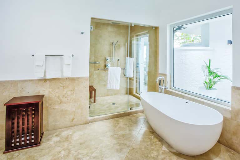 Luxury bathroom with freestanding white tub, large walk-in shower, and natural stone accents