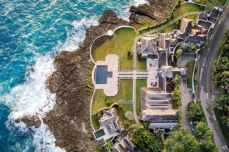 Luxury oceanfront villa with curved pool overlooking rocky coastline