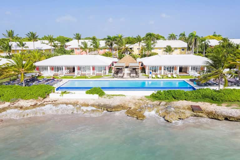 Beachfront resort with rectangular pool, white cabanas, and turquoise ocean waters beyond