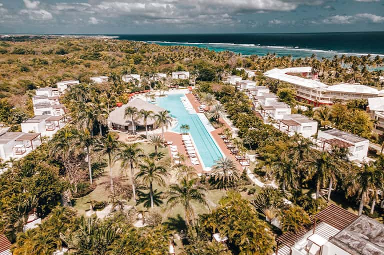 Aerial view of resort with Olympic-length pool, palm trees, and ocean backdrop