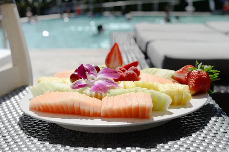 Elegant fruit and sashimi platter with flowers by pool area