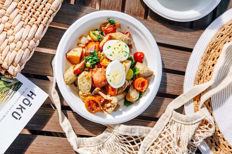 Gourmet salad plate with potatoes, greens, and egg on wooden table