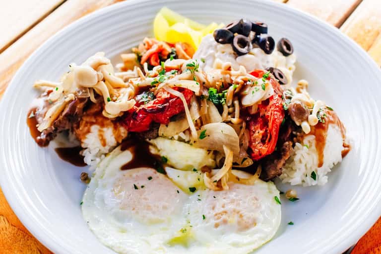 Asian noodle dish with vegetables and protein on white plate at poolside dining