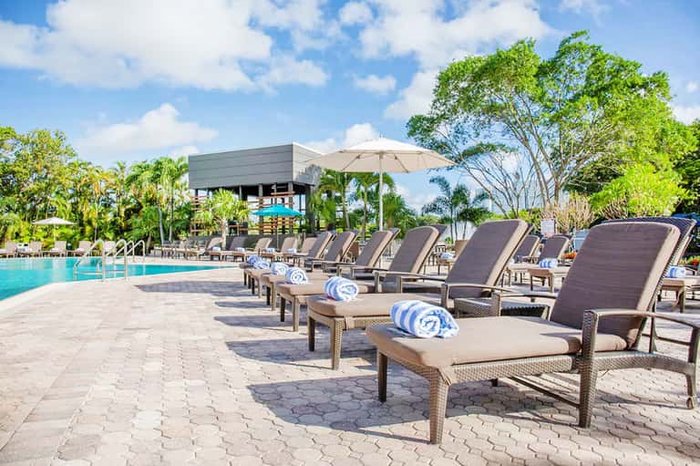 Resort poolside with lounge chairs, umbrellas, and lush tropical landscaping