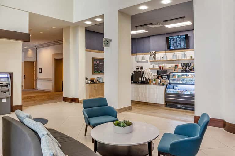 Modern hotel lobby lounge with blue chairs, coffee bar, and seating areas