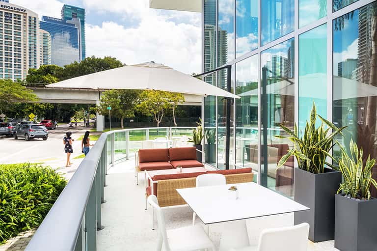 Urban terrace patio with umbrellas, wicker furniture, and glass railings overlooking downtown