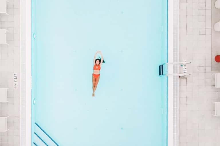 Woman floating in light blue indoor lap pool viewed from above