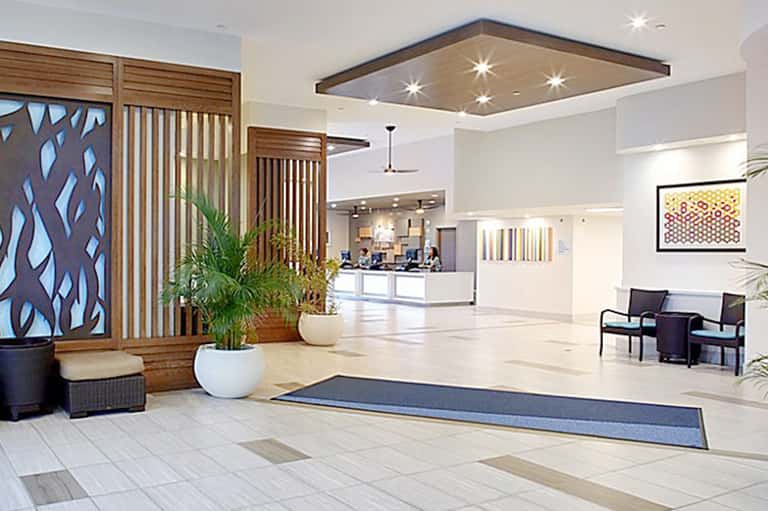 Modern hotel lobby with wooden accents, white marble floors, and contemporary reception desk