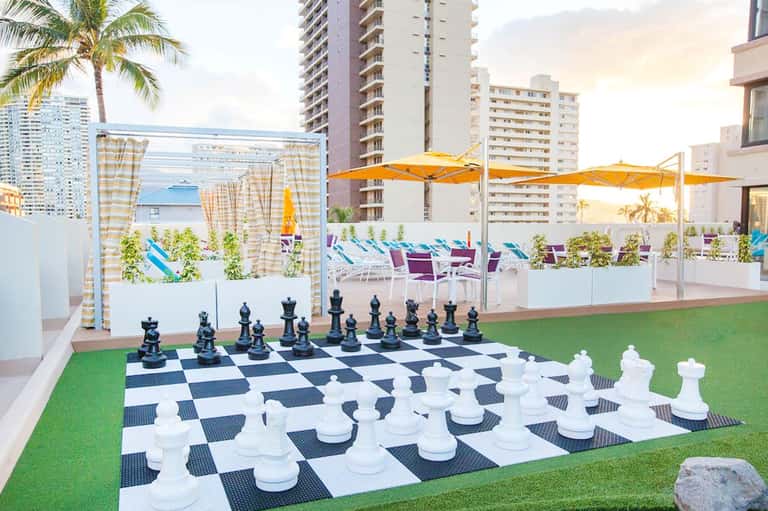 Rooftop terrace with giant chess set, yellow umbrellas, and city skyline views