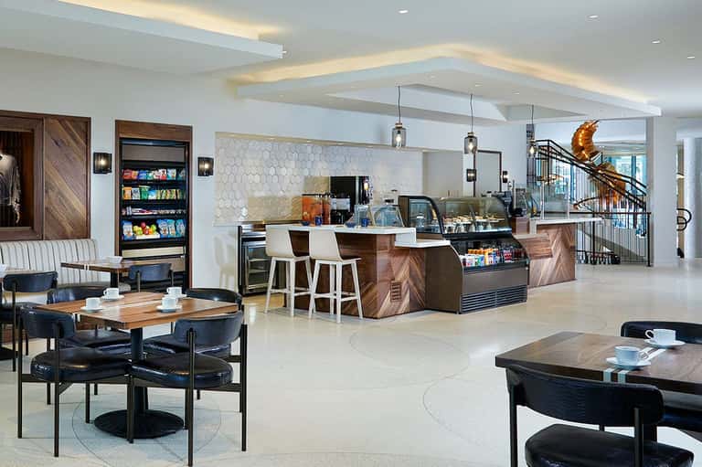Modern hotel lobby and café with wood accents, counter seating, and contemporary pendant lighting