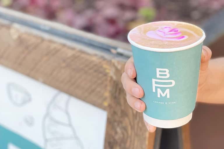 Hand holding a turquoise coffee cup with latte art from BYM Coffee & Wine cafe