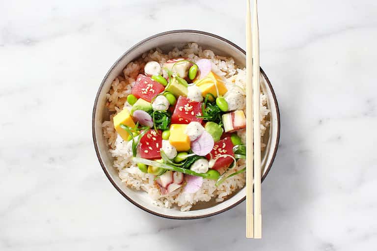 Asian rice bowl with vegetables and chopsticks on marble countertop