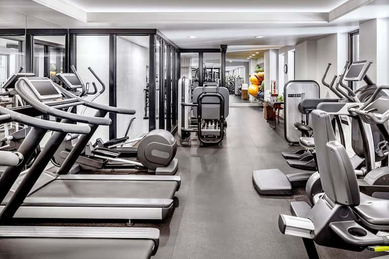 Modern fitness center with rows of treadmills, elliptical machines, and exercise equipment