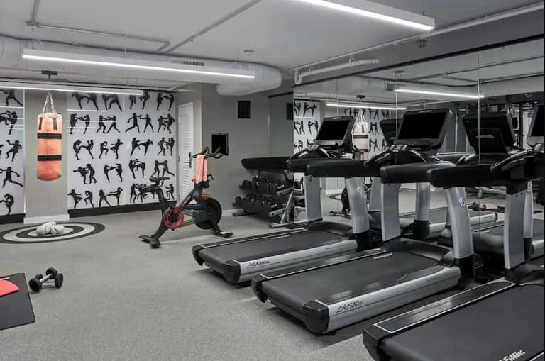 Contemporary fitness center with treadmills, exercise bike, boxing bag, and motivational wall graphics