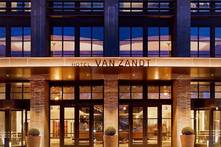 Hotel Van Zandt illuminated facade at dusk with large windows and brick exterior