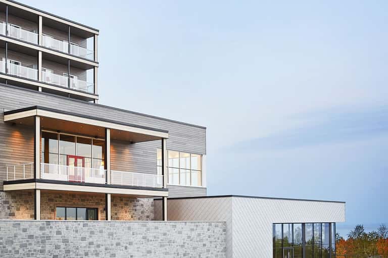 Modern multi-story residential building with white railings and geometric facade design