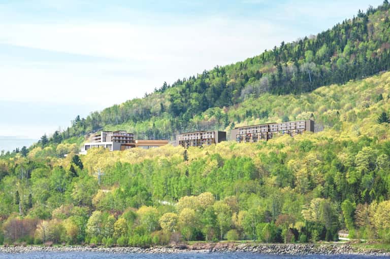 Modern resort buildings nestled on a forested hillside overlooking a lake