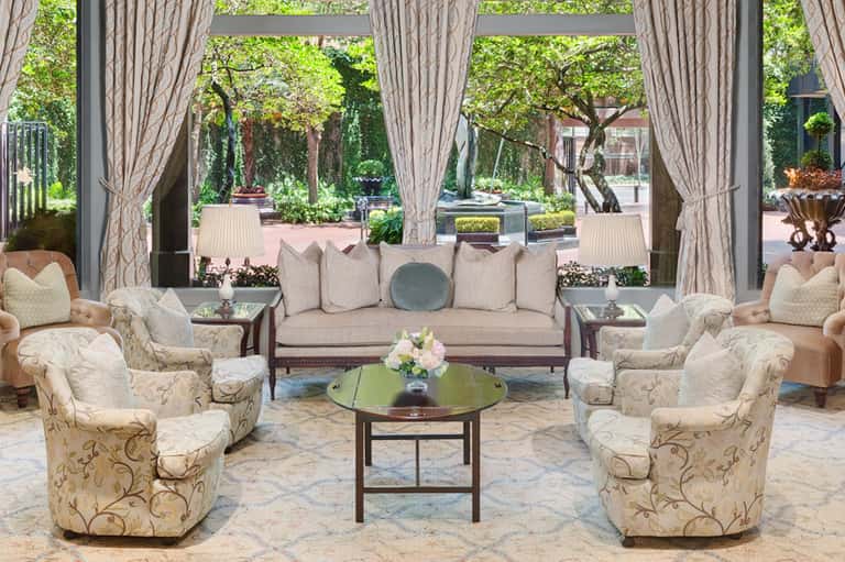 Elegant lounge area with cream furnishings, large windows overlooking manicured gardens