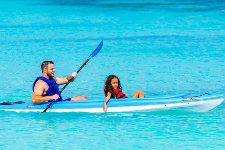Man and child kayaking together in bright turquoise tropical water