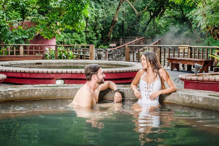Couple relaxing in natural hot spring surrounded by forest