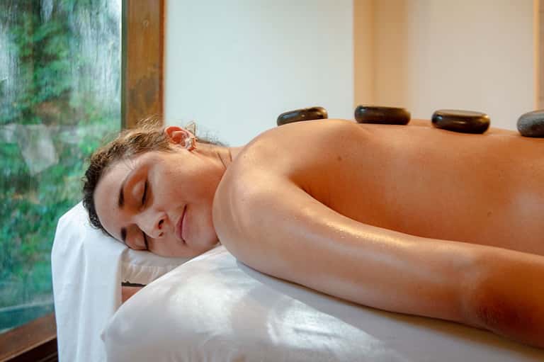Woman receiving hot stone massage treatment at spa wellness center