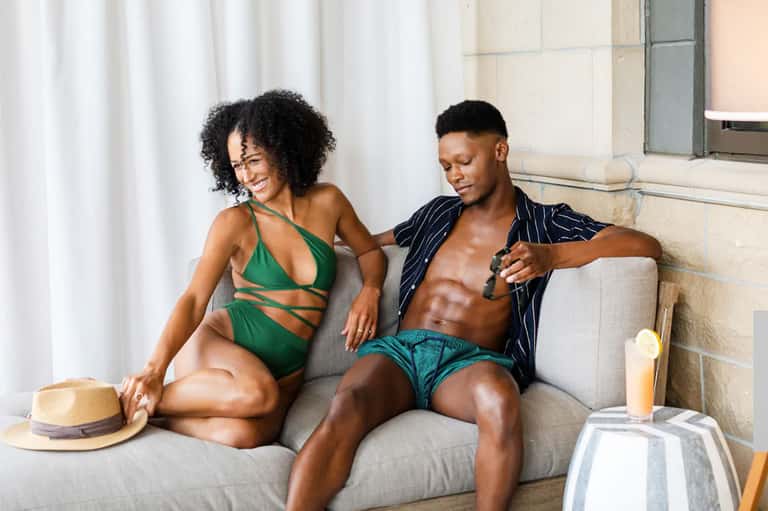 Couple relaxing on hotel suite sofa with ocean view and modern interior decor