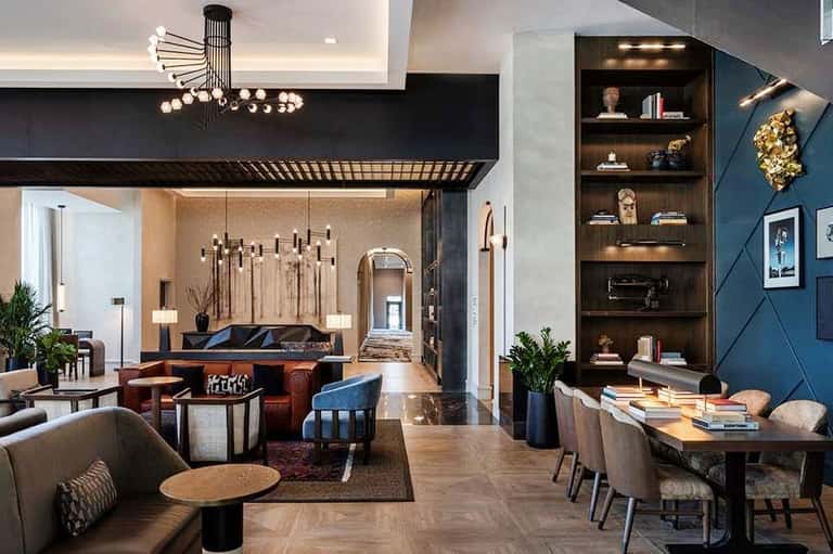 Luxury hotel lobby with high ceilings, modern lighting, leather seating, and blue accent wall