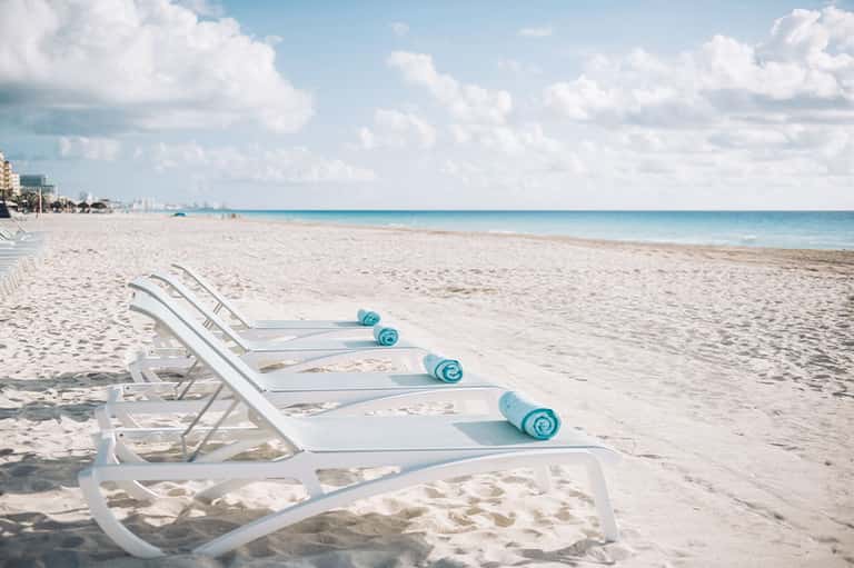 Beach lounge chairs with ocean and buildings visible along coastline