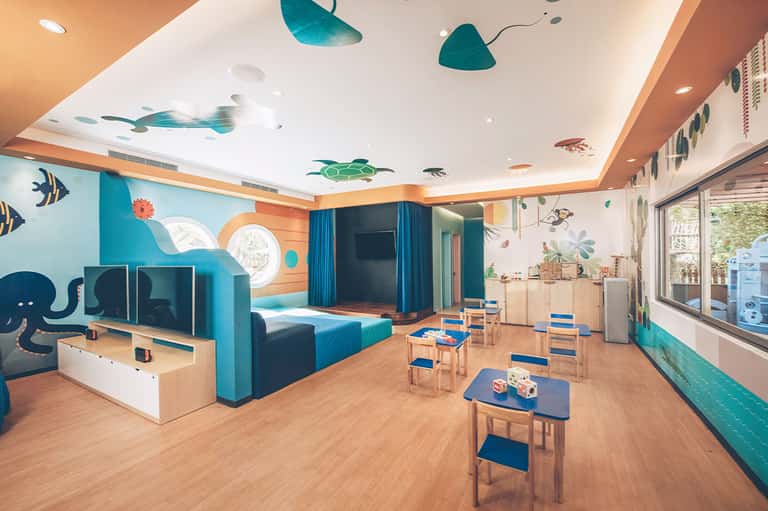 Colorful children's play room with ocean-themed wall art, blue furniture, and educational toys