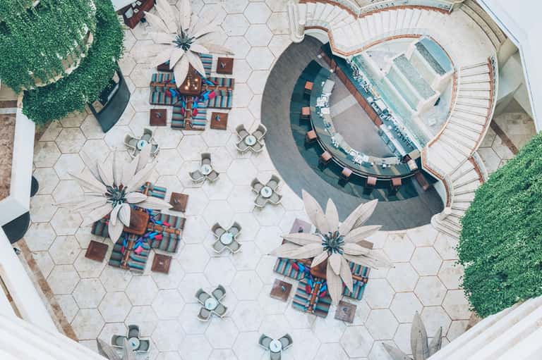 Aerial view of resort courtyard with geometric lounge areas, circular pool, and manicured landscaping