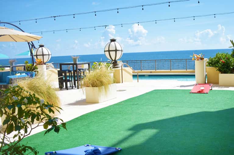 Rooftop terrace with mini golf course, ocean view, pool, and string lights at luxury beachfront resort
